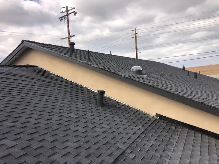 A newly installed shingle roof by Dynamic Roofing Inc. under a cloudy sky, featuring uniform dark shingles and multiple vent pipes in Antioch.