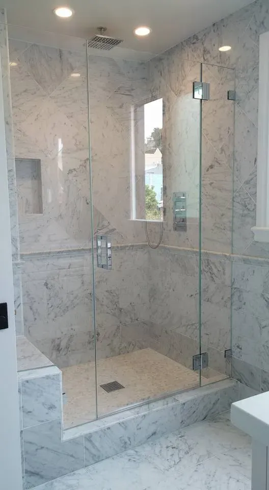 Luxurious marble shower with glass doors and a built-in bench, designed by East Bay PC Construction, Inc. in Brentwood.