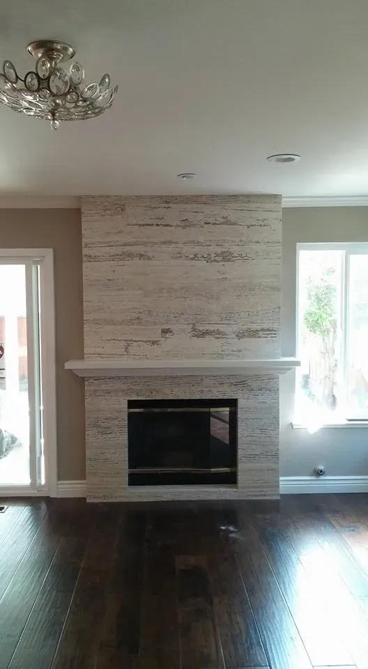 A modern living room in Brentwood featuring a sleek fireplace with light stone surrounding, crafted by East Bay PC Construction, Inc.