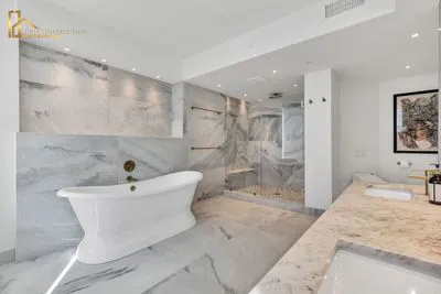 A modern bathroom featuring a freestanding bathtub, large marble tiles, and a spacious shower designed by Edri Construction.