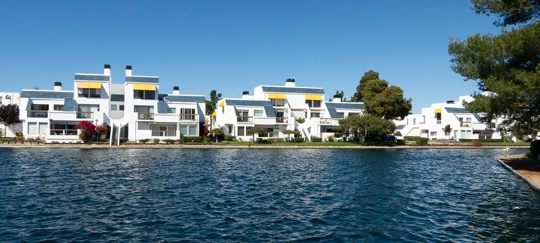 "Modern white waterfront buildings with yellow accents and a clear blue sky, showcasing El Gato Painting & Restoration, Inc.'s work in Mountain View."