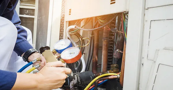A technician adjusting gauges on an HVAC system, showcasing detailed inspection and repair work, representing Electro-Integrity's services in San Francisco.