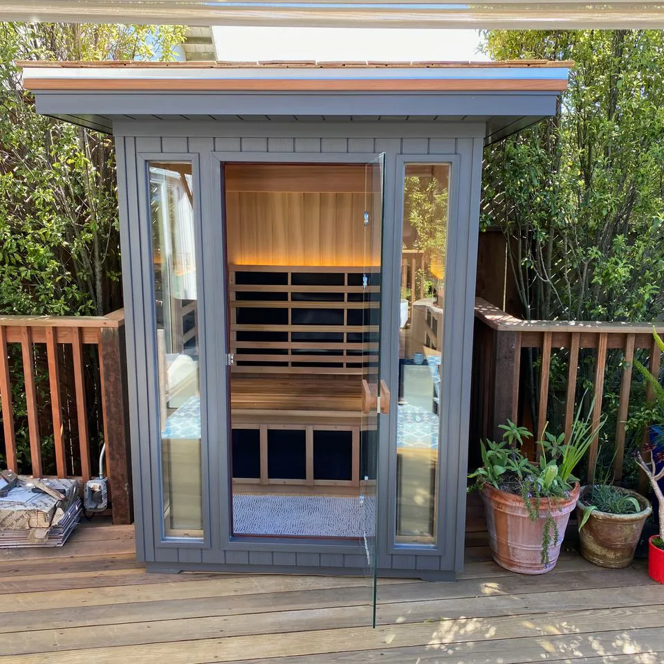 A modern outdoor sauna with glass doors and wooden panels, surrounded by a wooden deck and plants, created by Electro-Integrity in San Francisco.