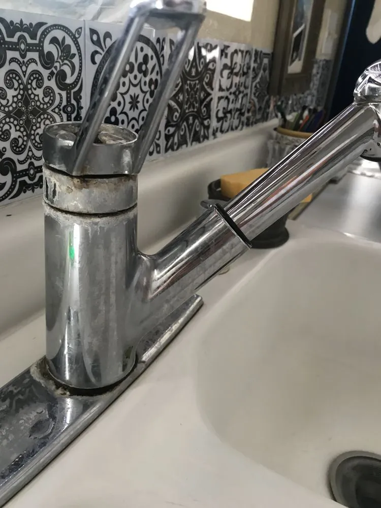 "A close-up of a kitchen faucet with signs of wear, highlighting the need for repair or maintenance."