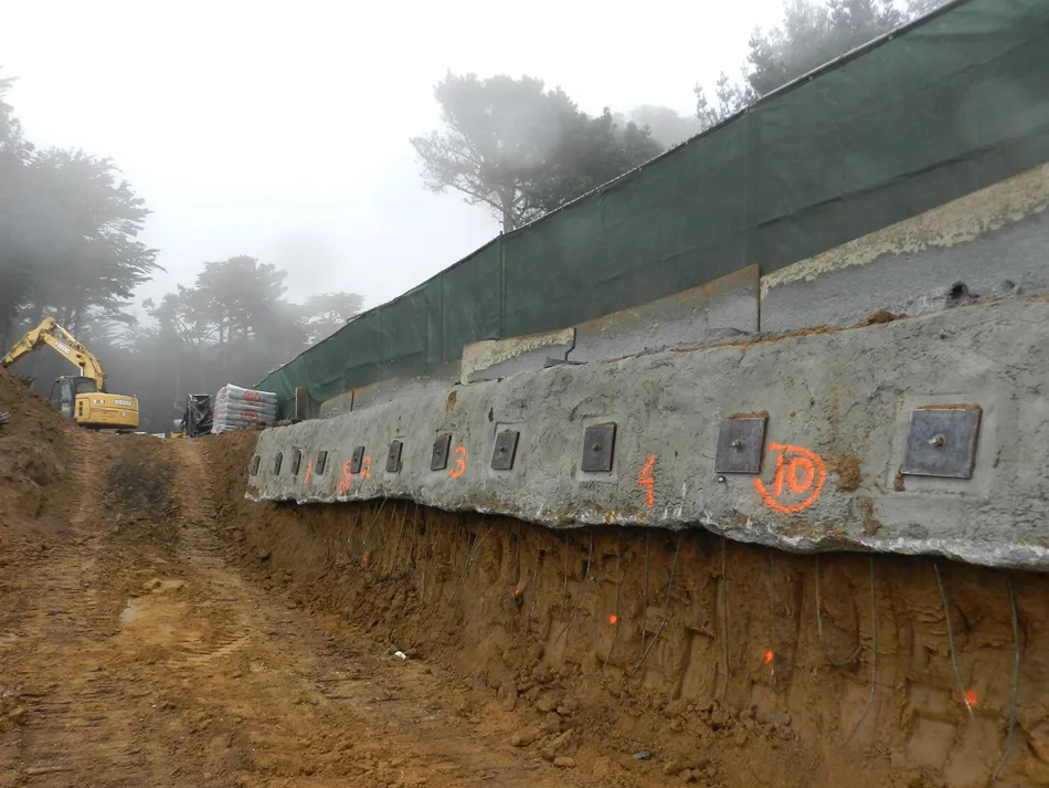 Image of a construction site in a foggy area, showing a soil stabilization project with numbered anchors and excavation work by Engineered Soil Repairs, Inc.