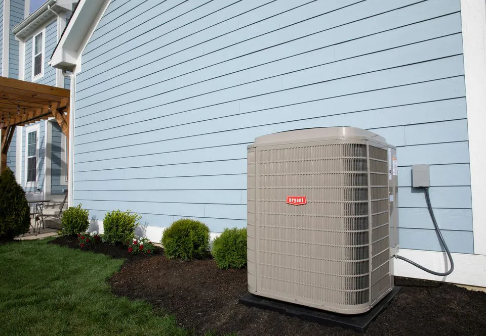 "An outdoor air conditioning unit installed beside a blue house, surrounded by a neatly landscaped garden, representing the services of Enviro Heating & Air Conditioning, Inc. in Rohnert Park."