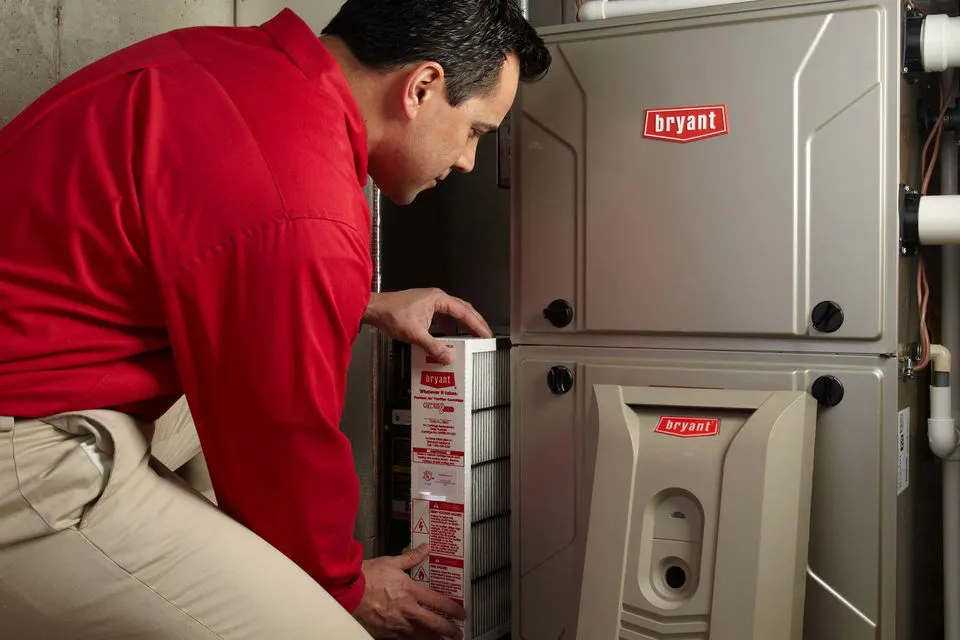 "Technician in red shirt changing the filter of a Bryant HVAC system for Enviro Heating & Air Conditioning, Inc. in Rohnert Park."