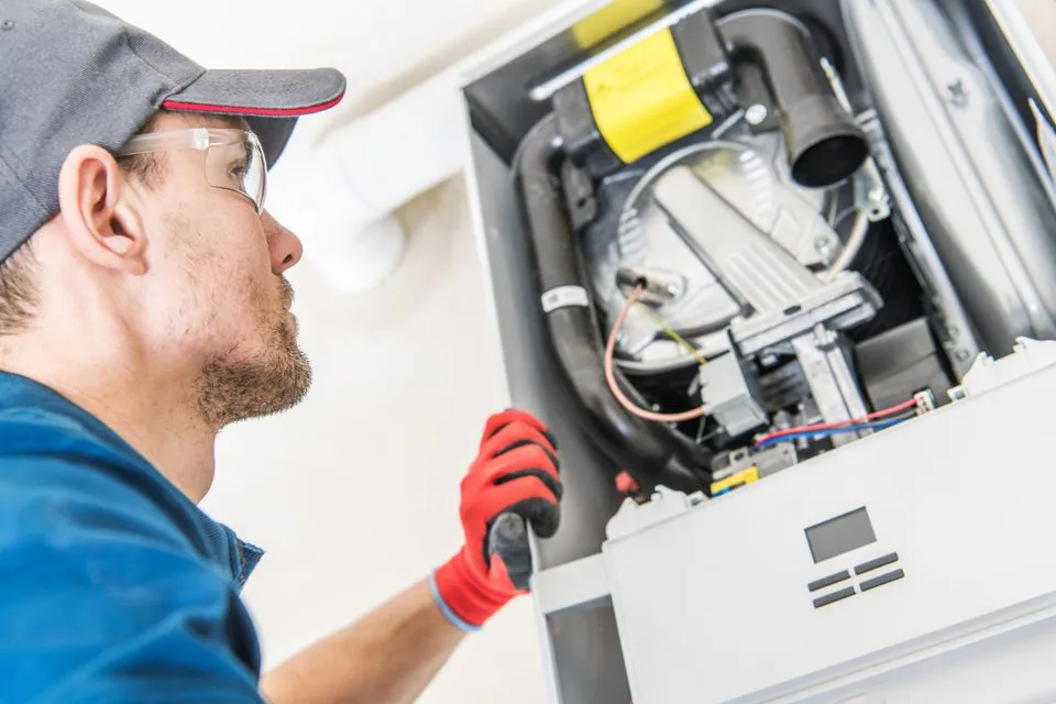 A technician from Enviro Heating & Air Conditioning, Inc. in Rohnert Park examines the interior of a heating unit.