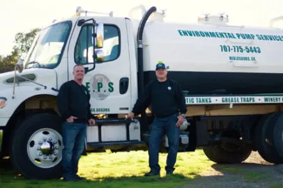 Two individuals standing beside a large Environmental Pump Services, Inc. truck in Healdsburg, showcasing their commitment to sustainable waste management.