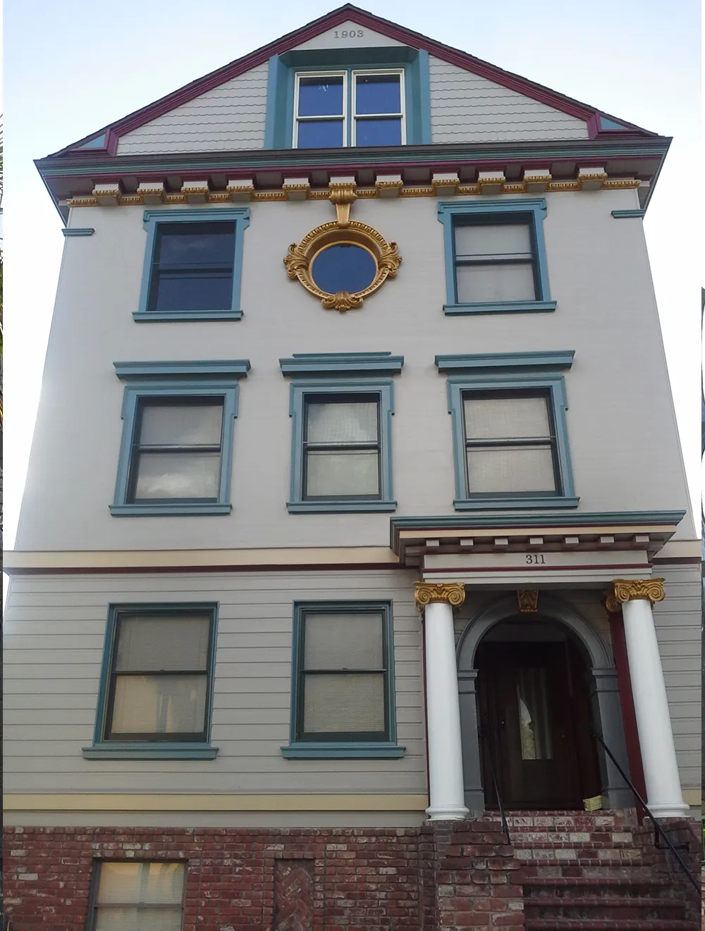 A historical building with detailed trim and an arched entrance, showcased by FaithPainting in San Jose.
