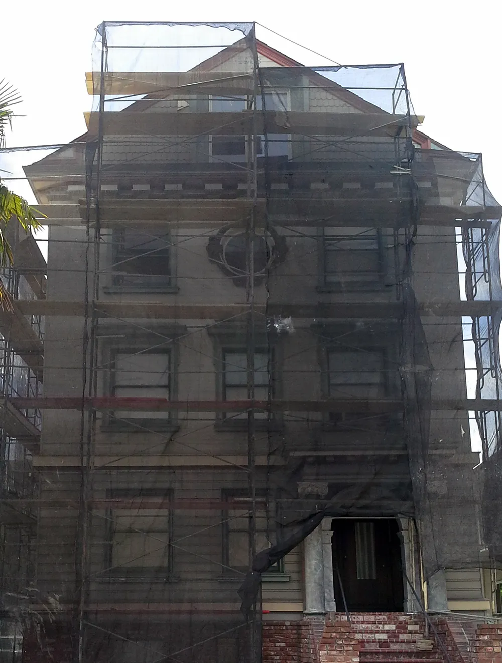 A multi-story building in SanJose covered with scaffolding and netting for a painting project by FaithPainting.