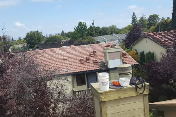 Rooftop view of a residential area in SanJose, showing roofing materials and equipment on a tiled roof, highlighting FalconRoofing's expertise.