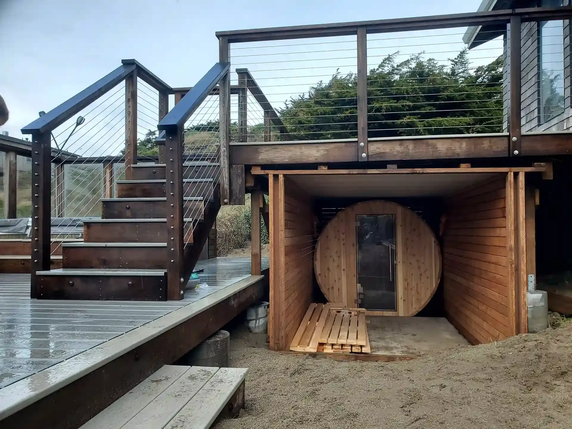 A custom wooden deck with stairs and metal railing, built by Farrar Construction Inc. in Petaluma, featuring an integrated wooden sauna.