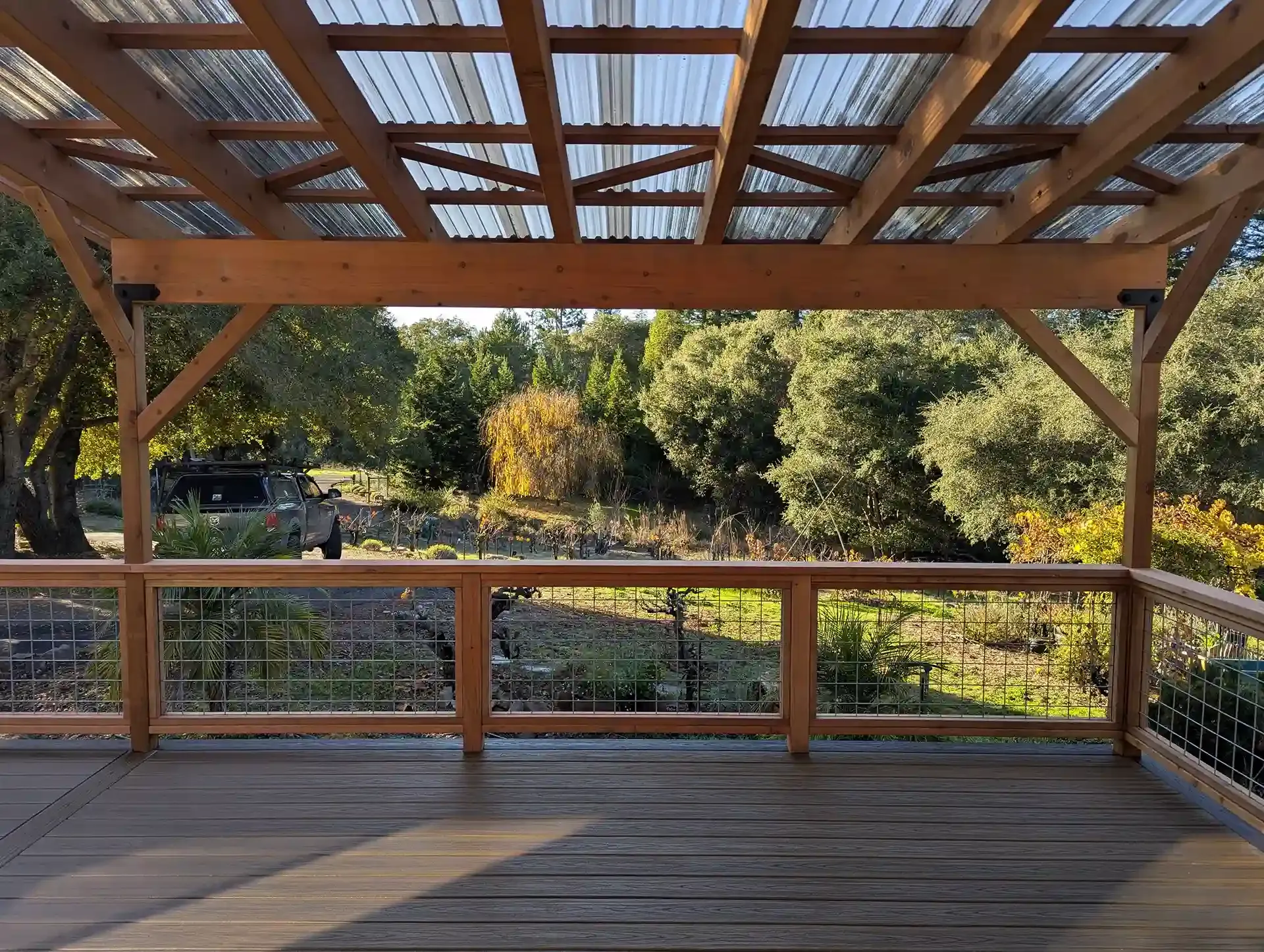 A wooden pergola with a transparent roof, overlooking a green landscape, constructed by Farrar Construction Inc. in Petaluma.