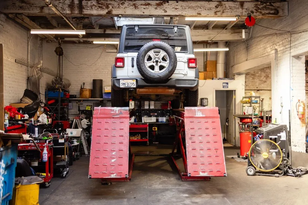 A vehicle lifted on a service platform inside a garage with tools and equipment at Faxon Garage in San Francisco.