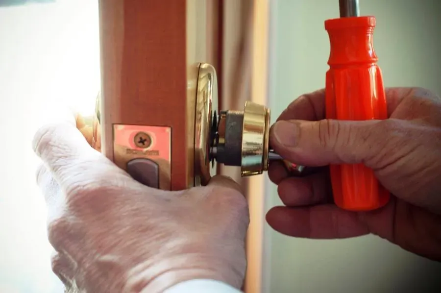 A close-up of a person using a screwdriver to install a lock on a wooden door, representing the security services offered by First Lock & Security Technologies in Los Altos.