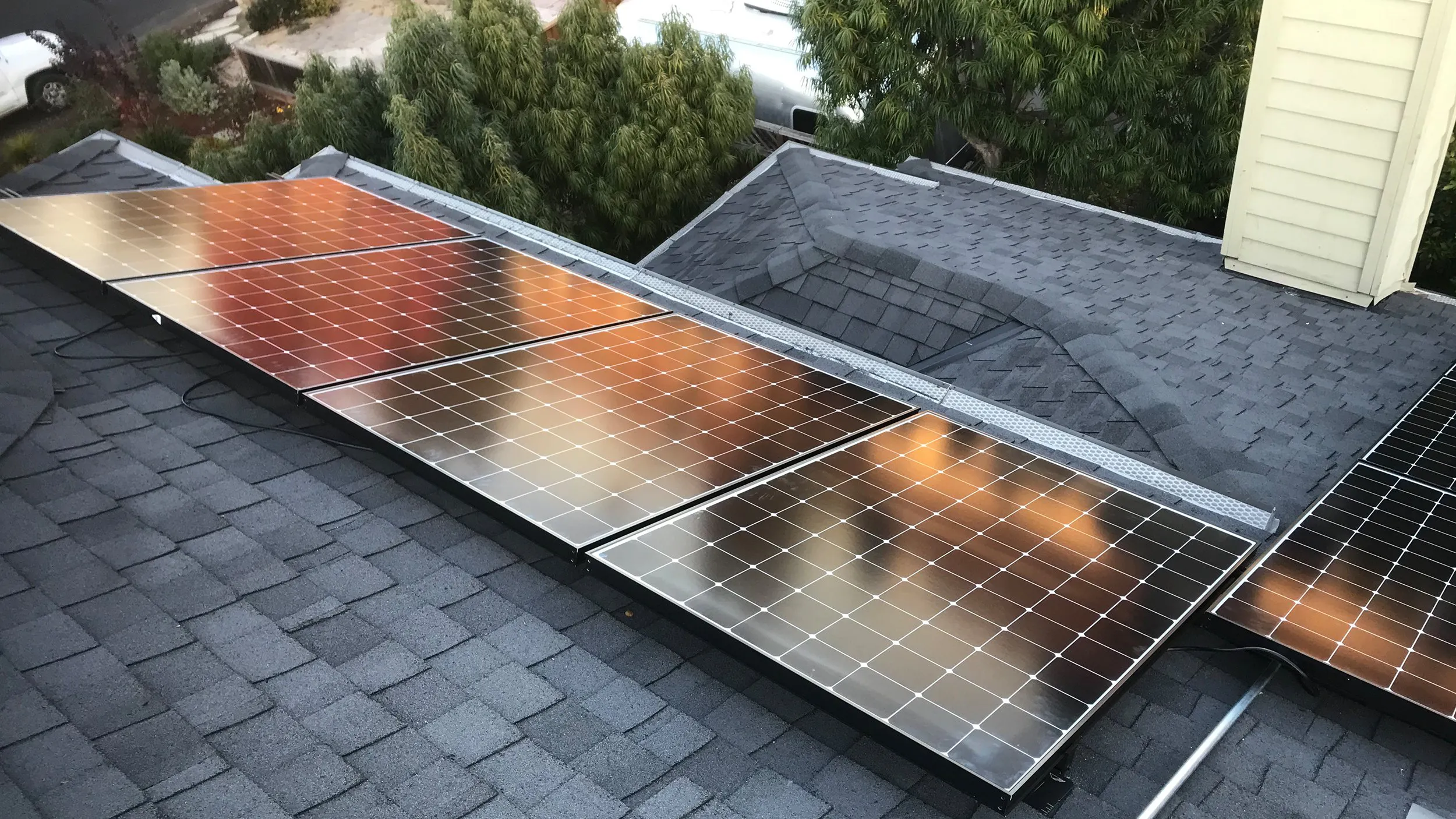 Rooftop solar panels installed by Freedom Solar, Inc. in Campbell, showcasing a sleek and efficient design on a shingled roof surrounded by trees.