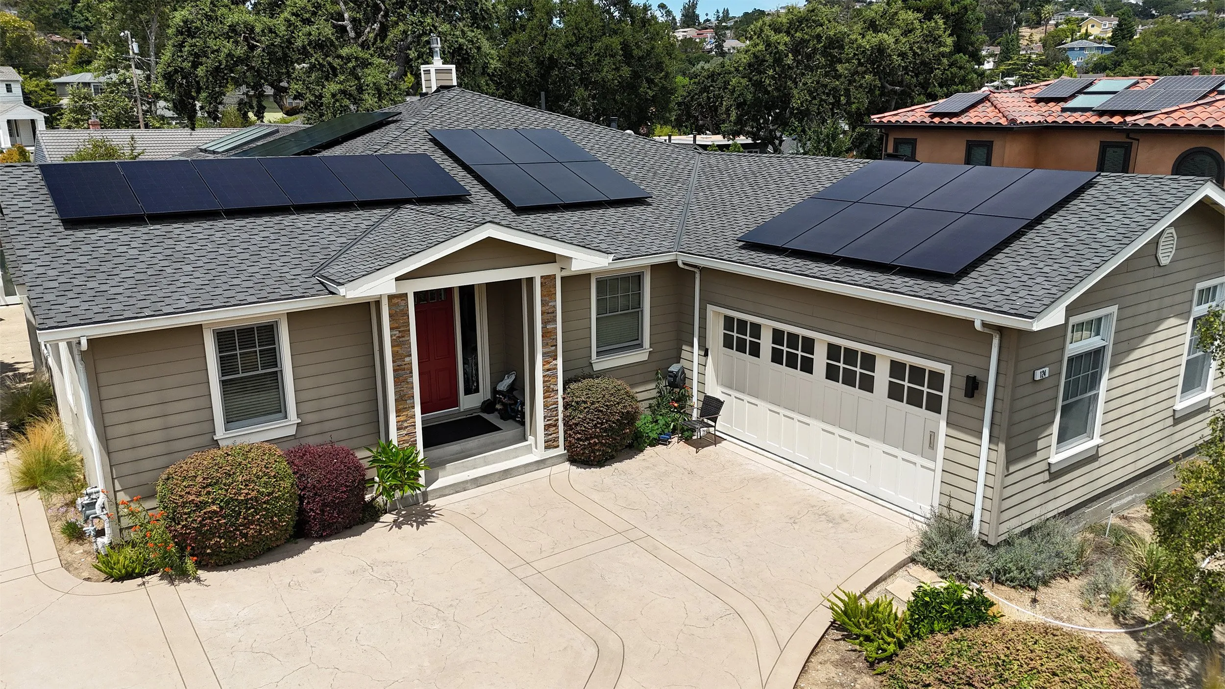 Residential home in Campbell with solar panels installed on the roof by Freedom Solar, Inc., set against a backdrop of trees and neighboring houses.