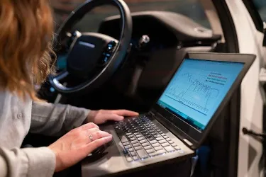 A person using a laptop connected to a vehicle's diagnostic system inside a car at Fremont Foreign Auto.