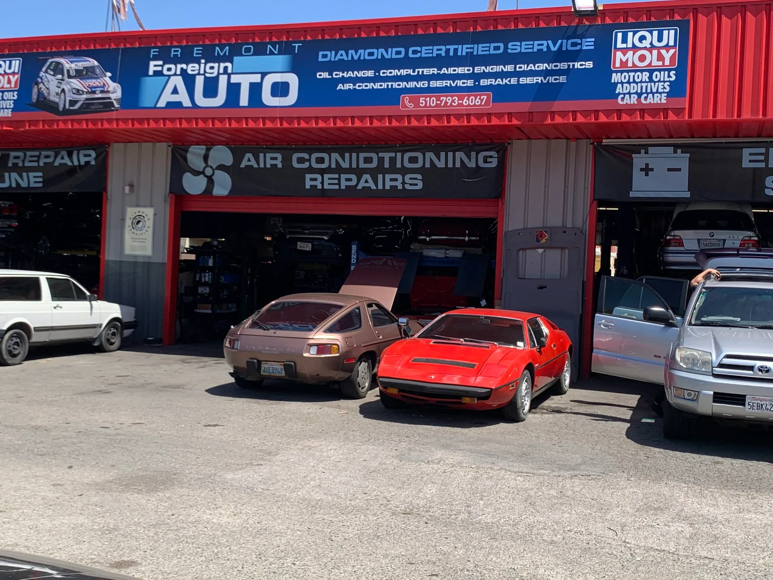 Exterior view of Fremont Foreign Auto in Fremont, showing classic cars parked outside the repair shop with a sign above highlighting services including air conditioning and engine diagnostics.