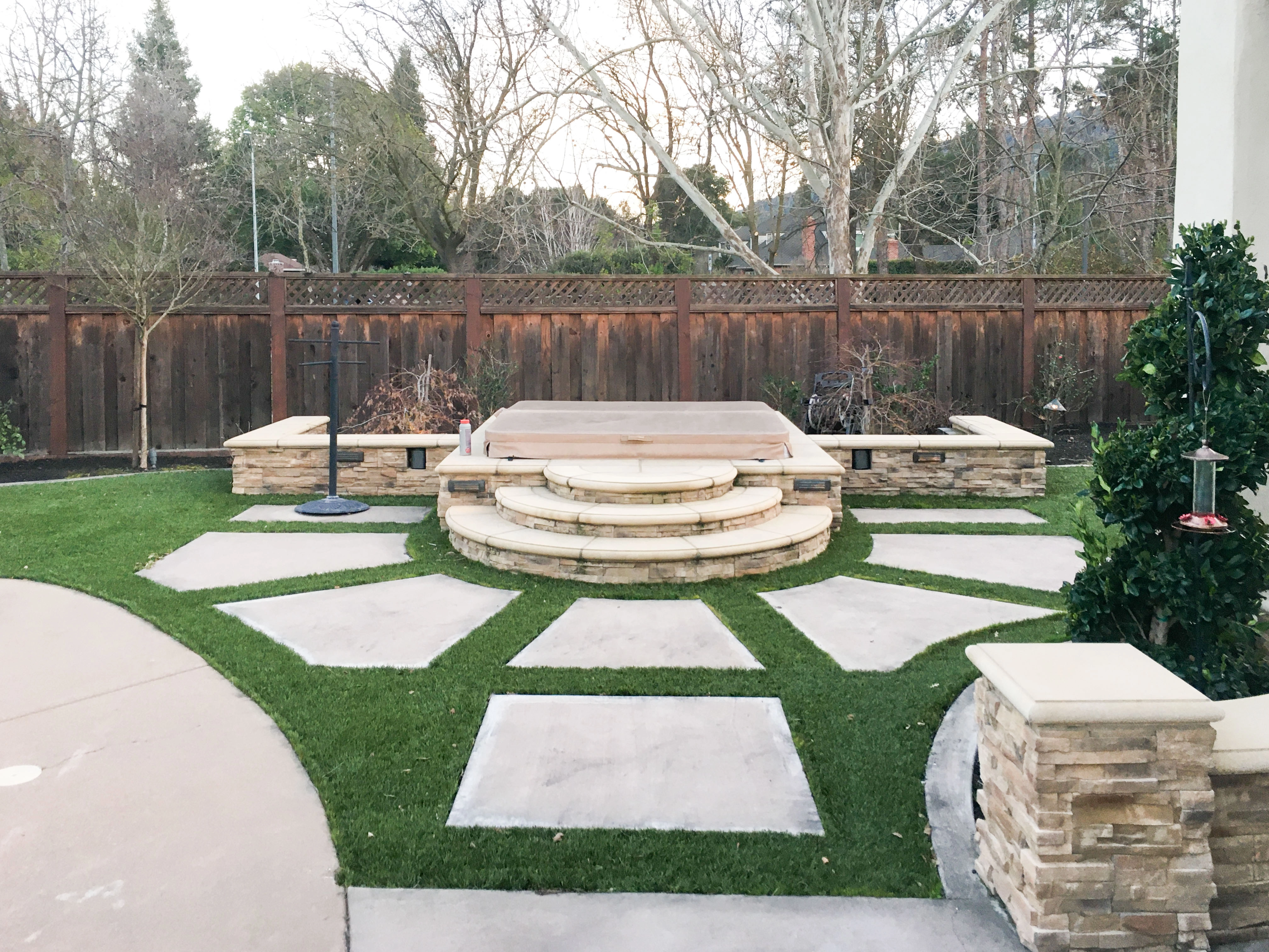 A well-designed backyard patio with stone steps, surrounded by greenery, created by GK Construction in Pleasanton.