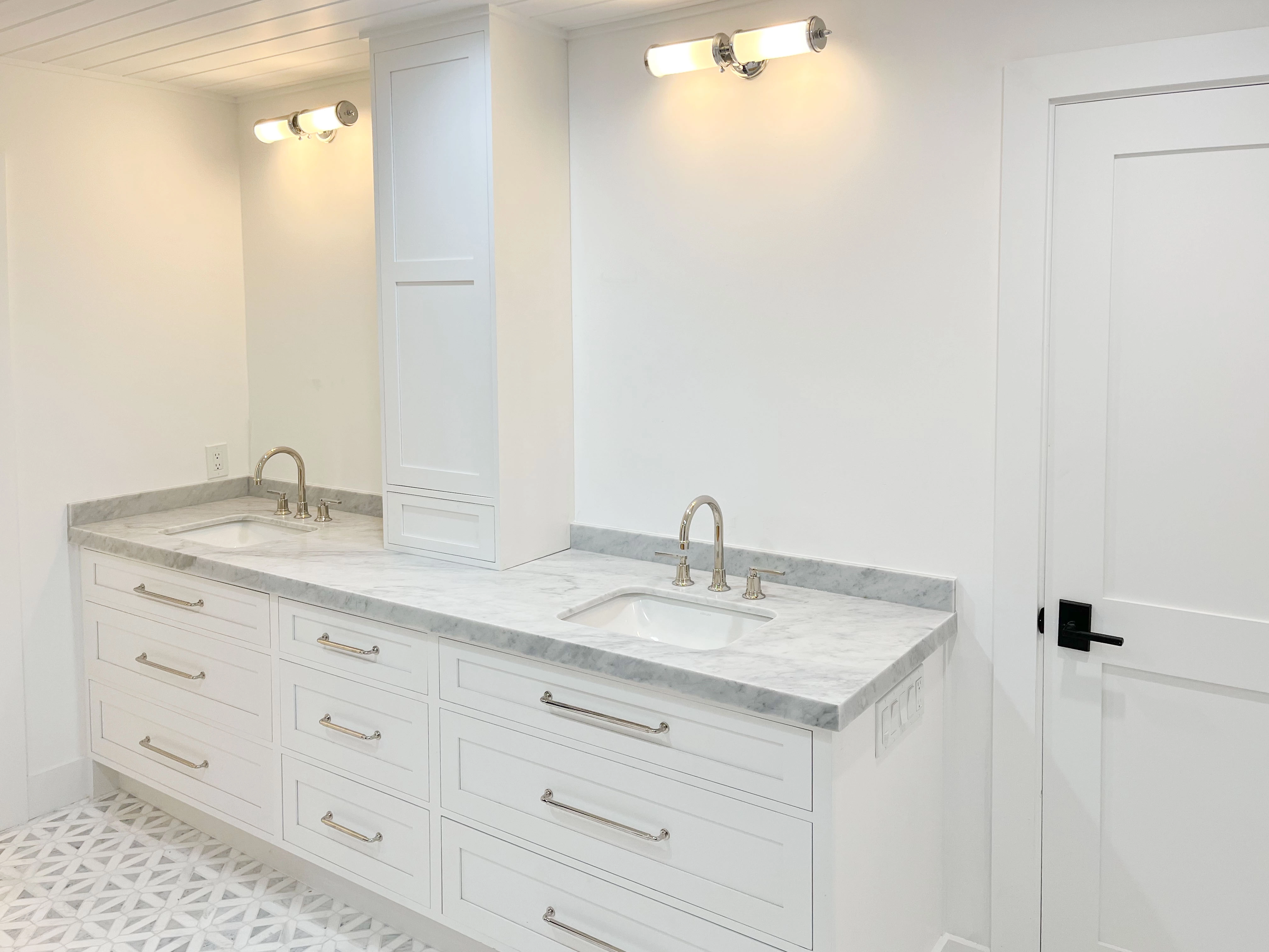 A modern bathroom with dual sinks and a white marble countertop, featuring sleek cabinetry and lighting, remodeled by GK Construction in Pleasanton.