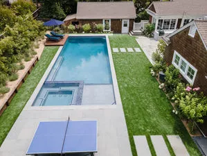 Aerial view of a landscaped backyard in San Rafael, featuring a modern rectangular pool with a connected hot tub, bordered by green lawns and patio areas, designed by G Landscape Division, LLC.