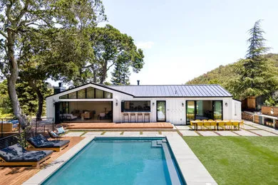 Modern backyard featuring a pool, patio area with seating, and well-manicured lawn surrounded by trees, designed by G Landscape Division, LLC in San Rafael.