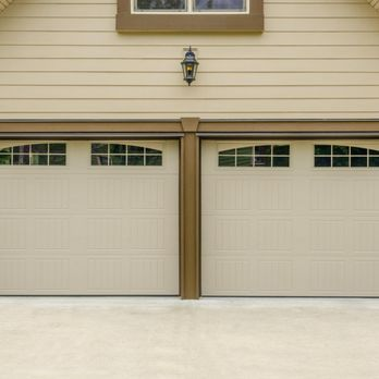 A well-maintained double garage door with a beige exterior and decorative windows, installed by Garage Door Experts Repair & Installation, LLC in Fremont.
