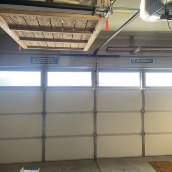 Interior view of a garage displaying a closed sectional garage door with small windows, located in Fremont, serviced by Garage Door Experts Repair & Installation, LLC.