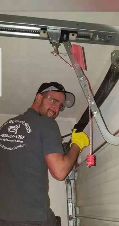 A garage door technician from Garage Door Pros working on a garage door mechanism in Sunnyvale, wearing safety gear and gloves.