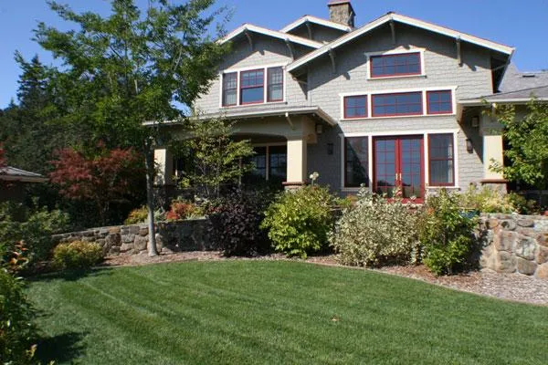 A beautiful house with a well-maintained garden and lush green lawn, featuring diverse shrubs and trees, exemplifying the landscaping work by Gill Landscape Inc. in Sebastopol.