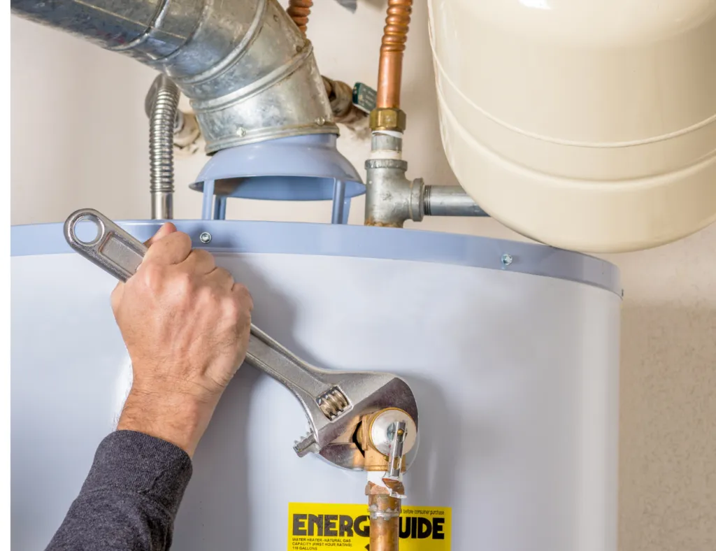A person using a wrench to tighten a pipe on a water heater showing the detailed plumbing work performed by Gladiator Repipe, Inc. in San Jose.