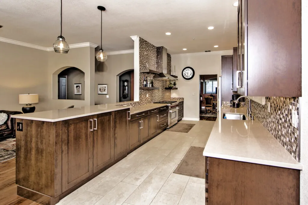 A modern kitchen with dark wood cabinetry, quartz countertops, pendant lighting, and stainless steel appliances, designed by Gold Hammer Construction, Inc. in Sebastopol.