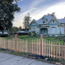 A newly installed wooden picket fence in front of a classic Victorian-style house in Cloverdale, showcasing the work of Gonzalez Fence Co.