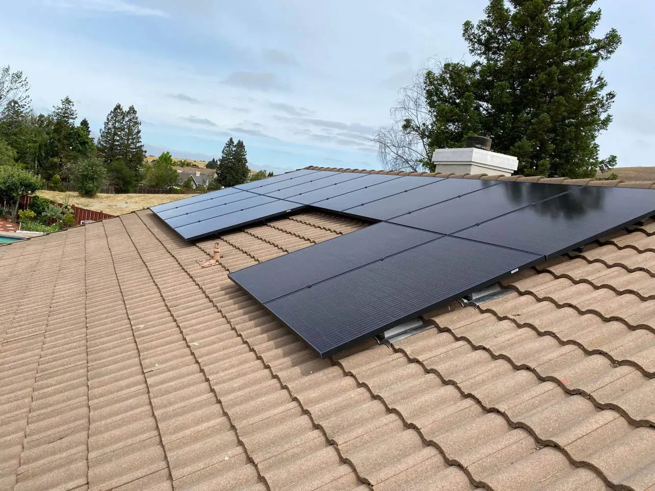 A rooftop with neatly installed solar panels surrounded by trees, exemplifying the solar energy solutions offered by Got Watts Electric, Solar & HVAC in Concord.