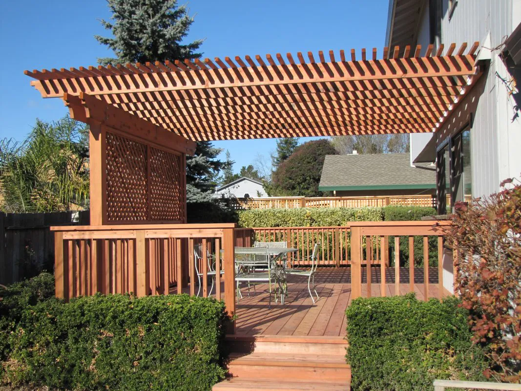 A wooden pergola with lattice panels and railings, built by Guy's Fencing, Inc., located in Windsor.