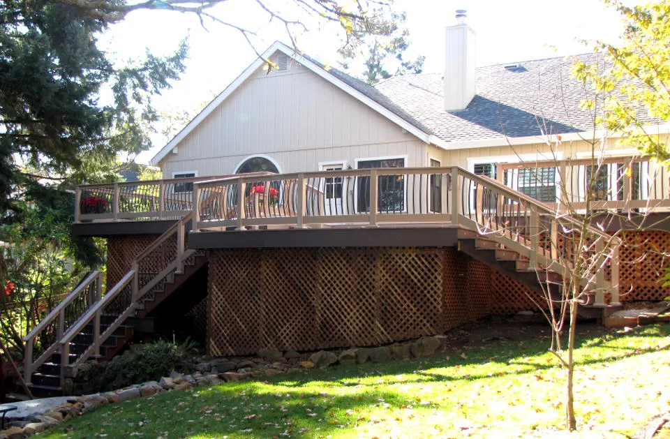 A well-constructed deck with railing and lattice skirting around a single-story house, highlighting the work of Guy's Fencing, Inc. in Windsor.