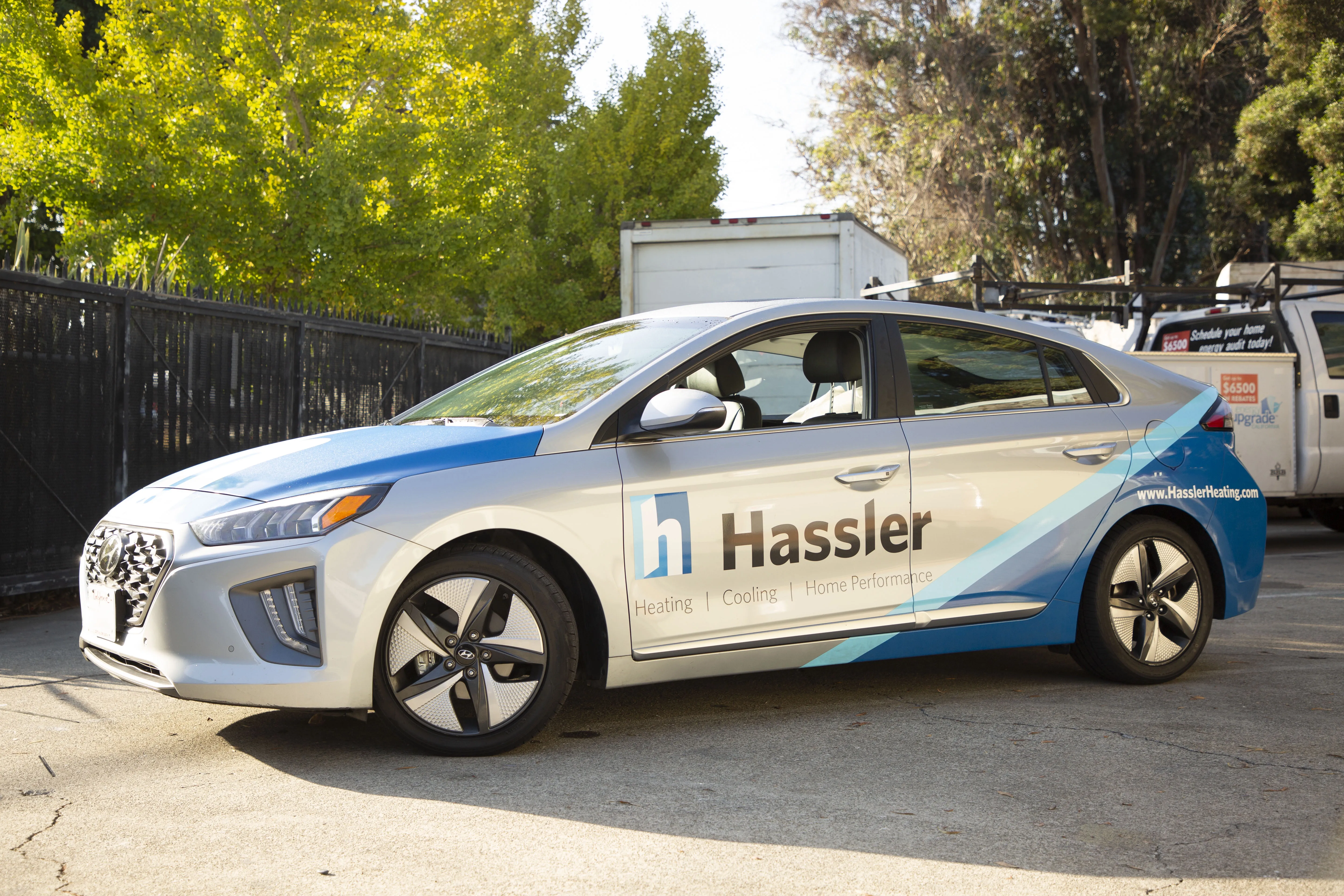 A branded car for Hassler Heating & Air Conditioning, LLC parked outdoors, showcasing its logo and services.
