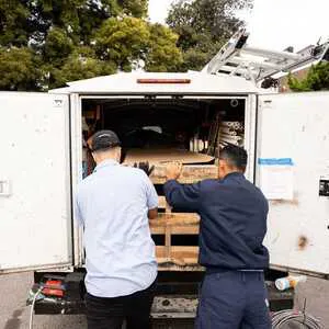 Two technicians organizing equipment in the back of a service van for Hassler Heating & Air Conditioning, LLC in El Cerrito.
