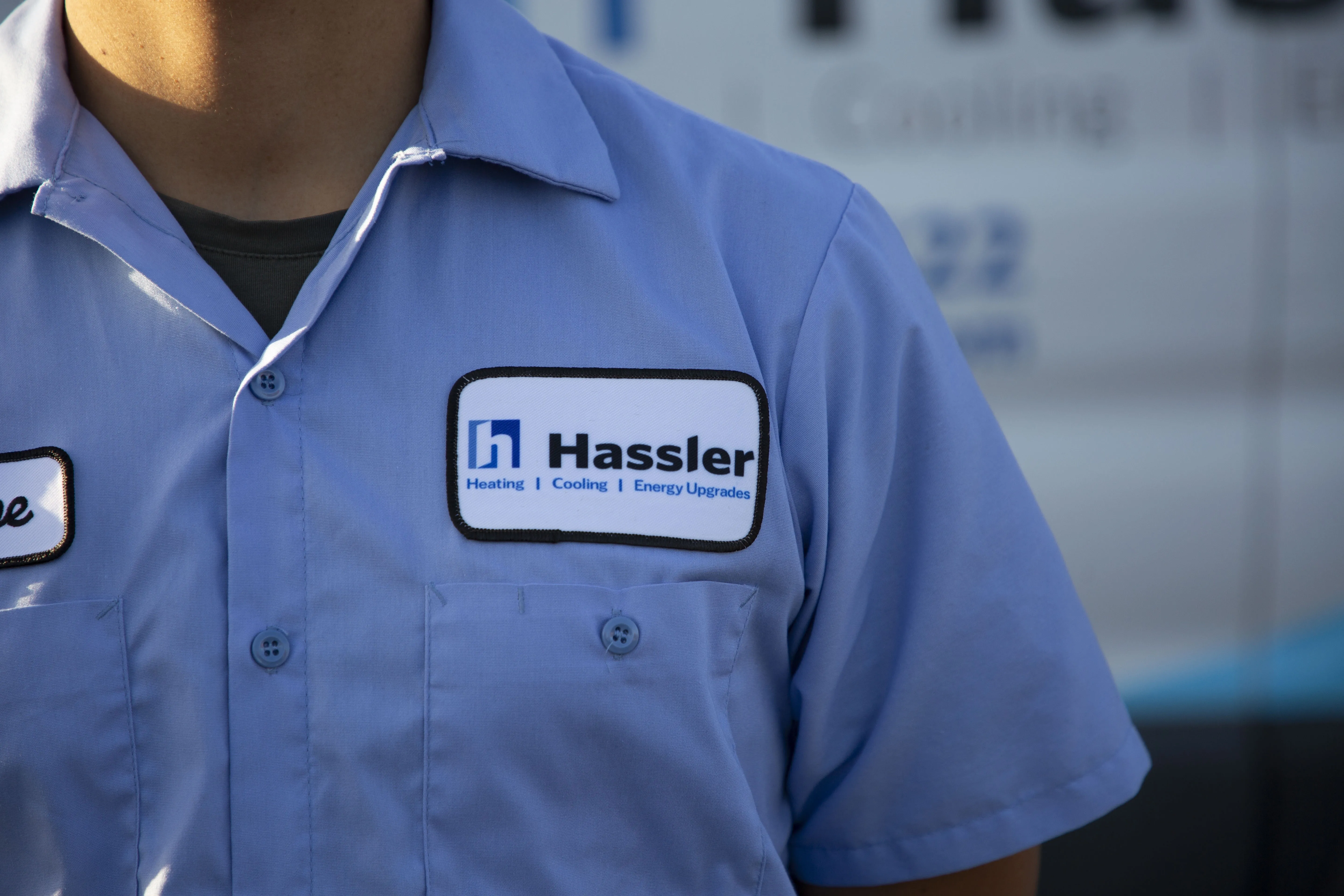 Close-up of a technician's uniform featuring the Hassler Heating & Air Conditioning, LLC logo and name tag in El Cerrito.