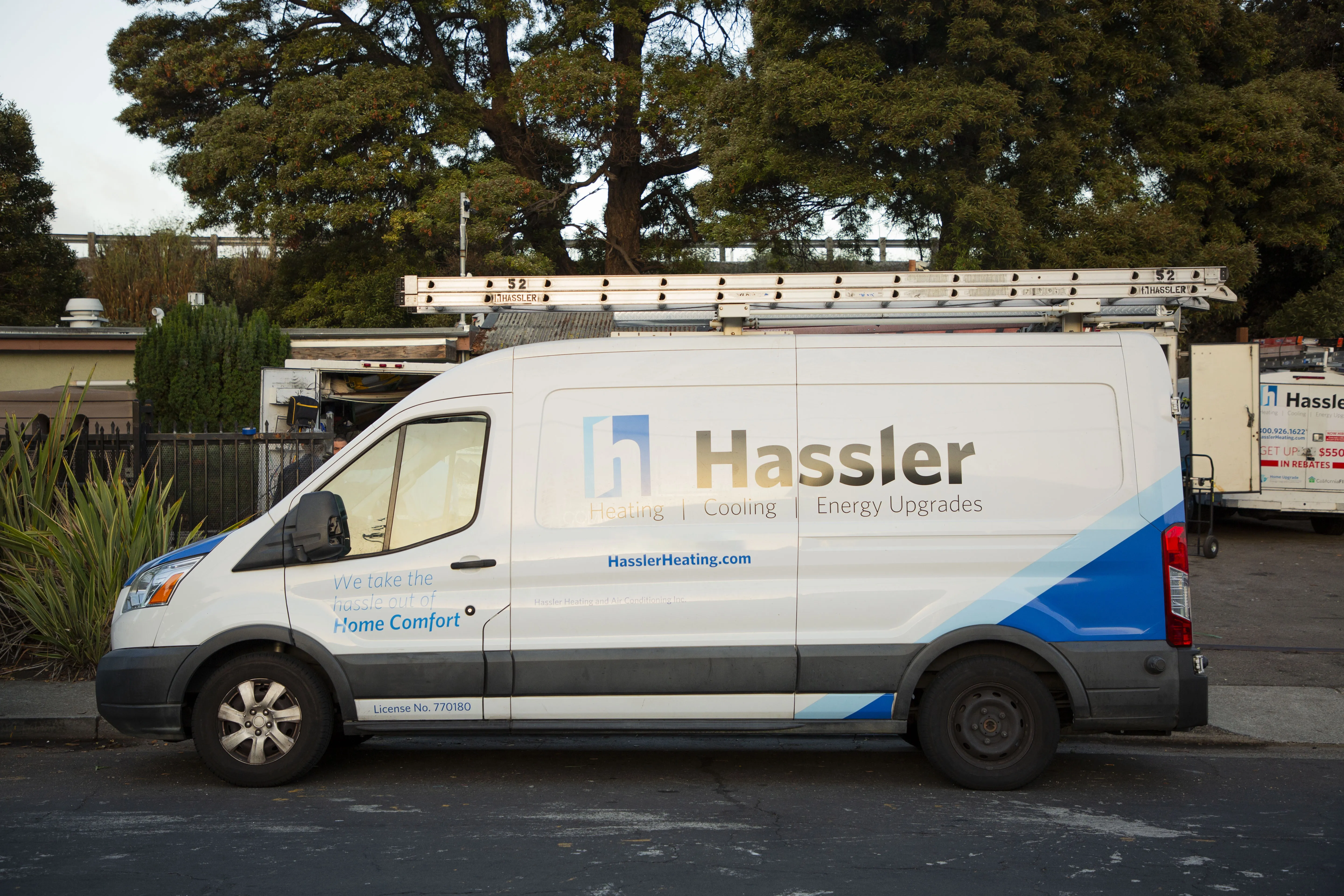 A Hassler Heating & Air Conditioning, LLC service van parked on a street in El Cerrito, equipped with a roof ladder and company branding.