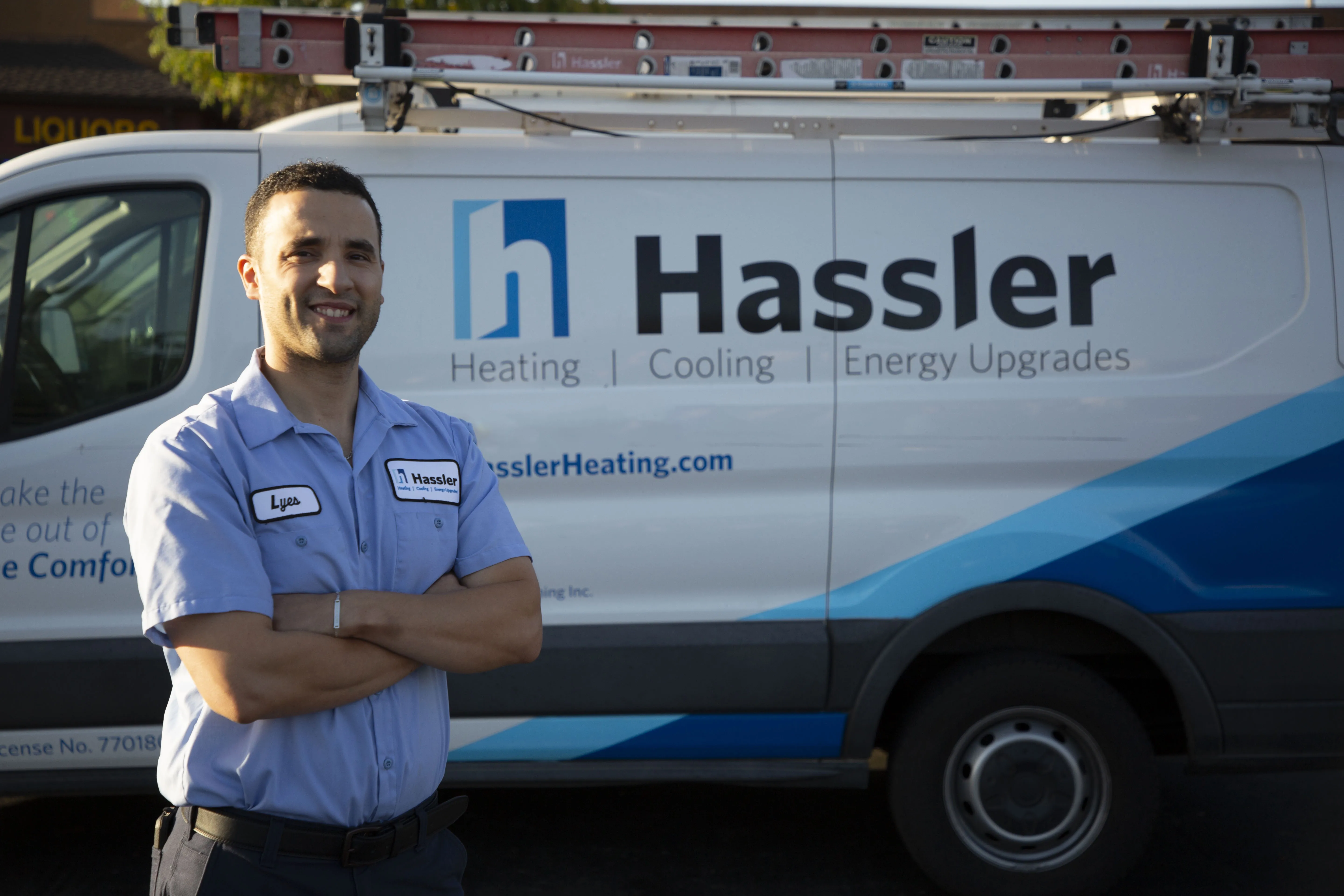 A technician from Hassler Heating & Air Conditioning, LLC, standing in front of a company van in El Cerrito.