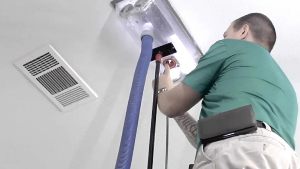 A technician from Heating And Air Experts in Fremont performs duct cleaning with specialized equipment.