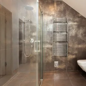 A modern bathroom featuring a glass-enclosed shower, sleek towel radiator, and contemporary fixtures, designed by Heavenly Touch in San Jose.