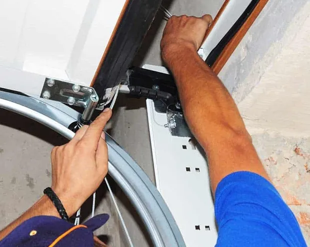 A person repairing a garage door mechanism, highlighting the precision and reliability of Help Garage Door services in Sacramento.
