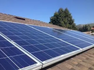 Rooftop solar panels installed on a sunny day by High Definition Solar in Concord, with clear blue sky and trees in the background.