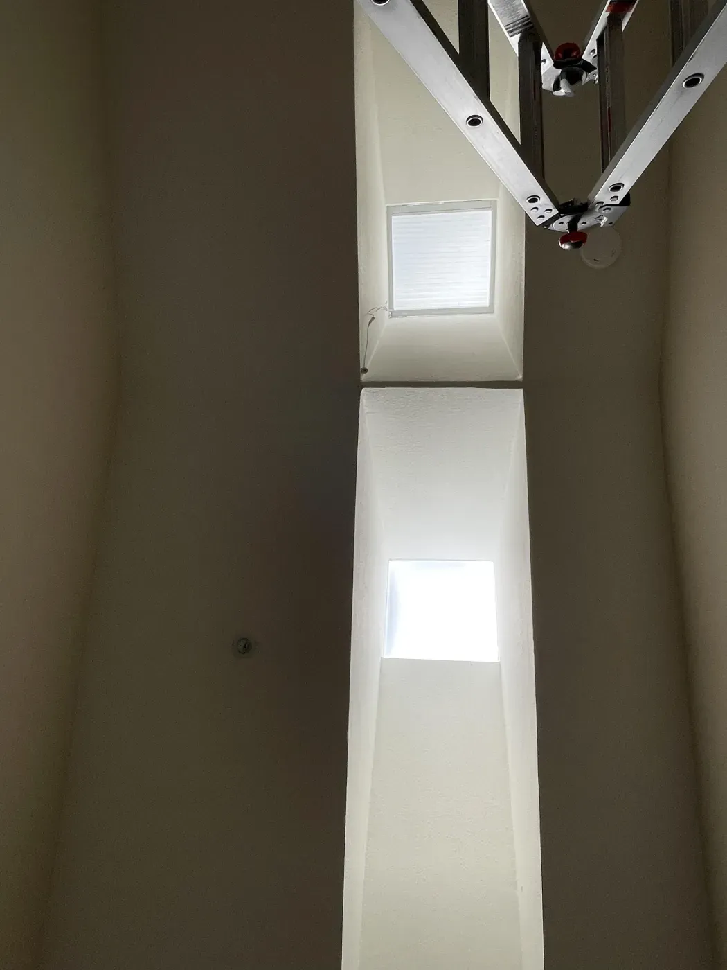 Interior view of two narrow, vertical windows with a ladder nearby, allowing natural light to illuminate the space, featuring window treatments by HomeLivingWindowFashions in Benicia.