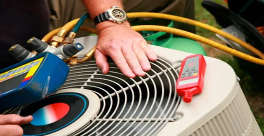 A technician performs maintenance on an air conditioning unit, adjusting controls and using diagnostic tools.