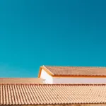 A rooftop with terracotta tiles under a clear blue sky, representing the roofing work of ImRoofingCompany in Pacifica.